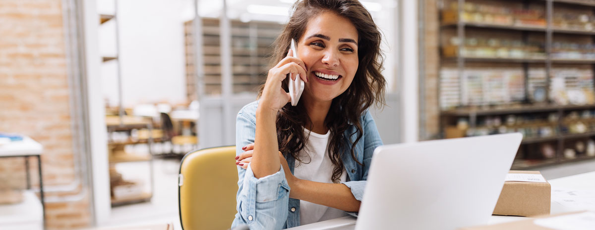 fröhliche frau arbeitet am laptop und telefoniert